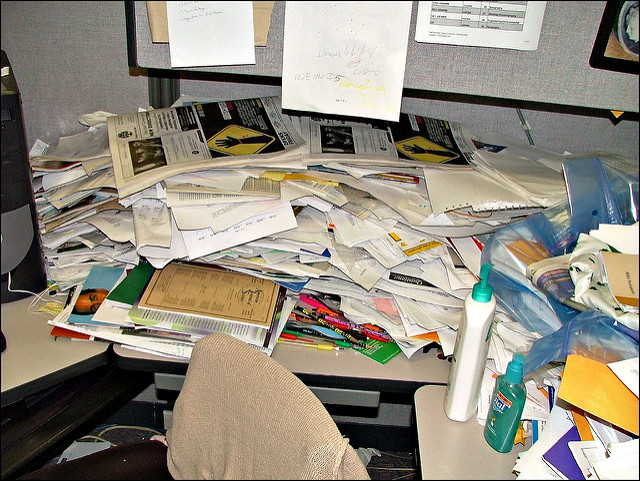 very messy office, desk covered in papers