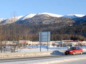 A mountain landscape with businesses and cars in the foreground.